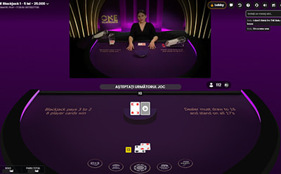 Crupier la masa One Blackjack live care așteaptă decizia unui jucător pentru următrul pas. 