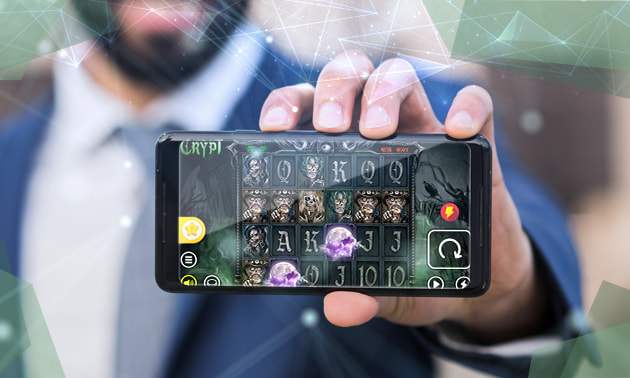 Slotul The Crypt pe un telefon, ținut de un om