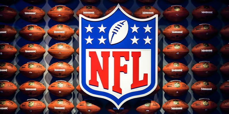 Logo-ul NFL în fața unui perete de mingi de fotbal american