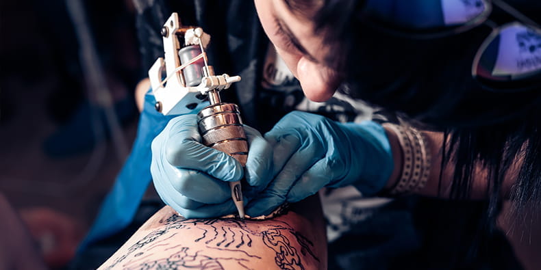 Artist de tatuaj care aplică cerneala pe piele
