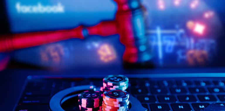 Jetoane de poker și un ciocan de judecător pe o tastatură de laptop.