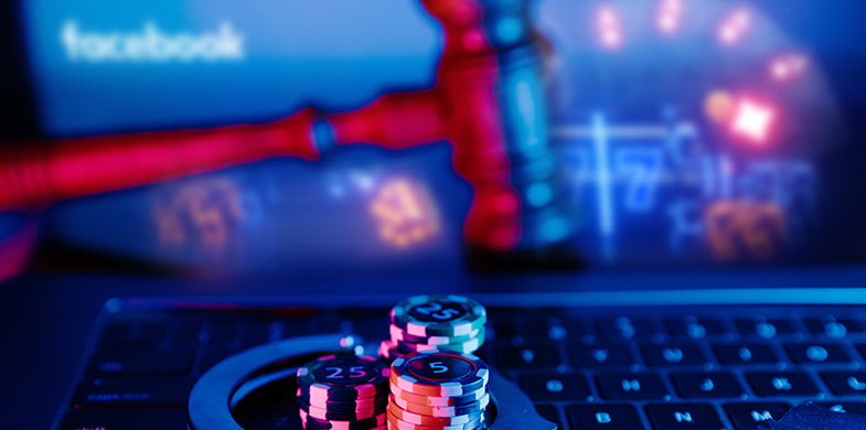 Jetoane de poker și un ciocan de judecător pe o tastatură de laptop.