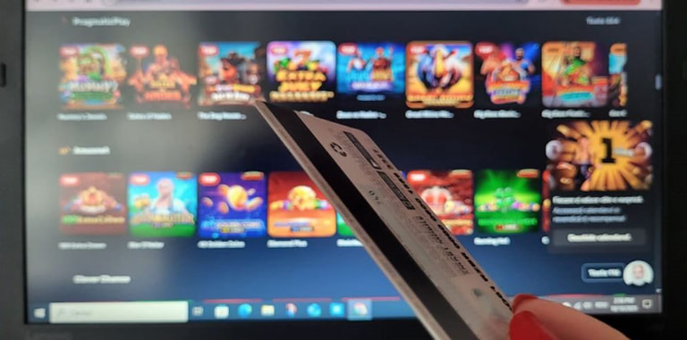 Card bancar în fața ecranului de laptop pe care este deschis un site de cazinou online