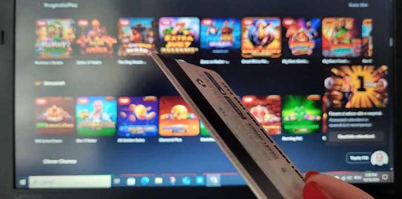 Card bancar în fața ecranului de laptop pe care este deschis un site de cazinou online